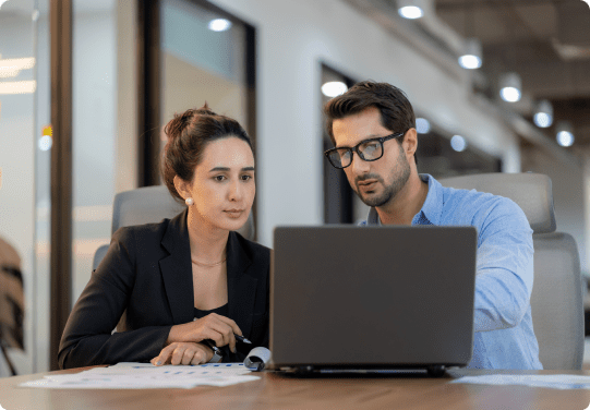 Two colleagues discussing work on laptop.